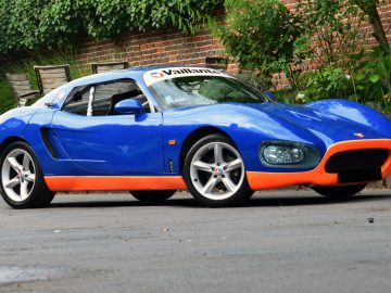 Een blauw-oranje Vaillant-sportwagen geparkeerd aan de kant van de weg.