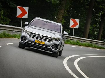 Een zilveren Volkswagen Touareg die over een bochtige weg rijdt.