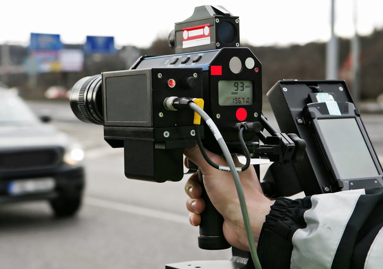 Een persoon die een camera vasthoudt op een weg met flitsers.