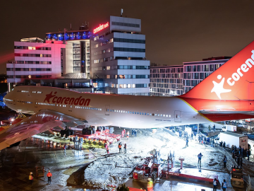 Een grote Boeing 747 geparkeerd voor een gebouw 's nachts.
