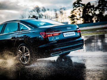 Een zwarte Audi S4 uitgerust met Vredestein-banden die op een natte weg rijdt.