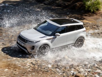 De witte Range Rover Evoque rijdt door water.