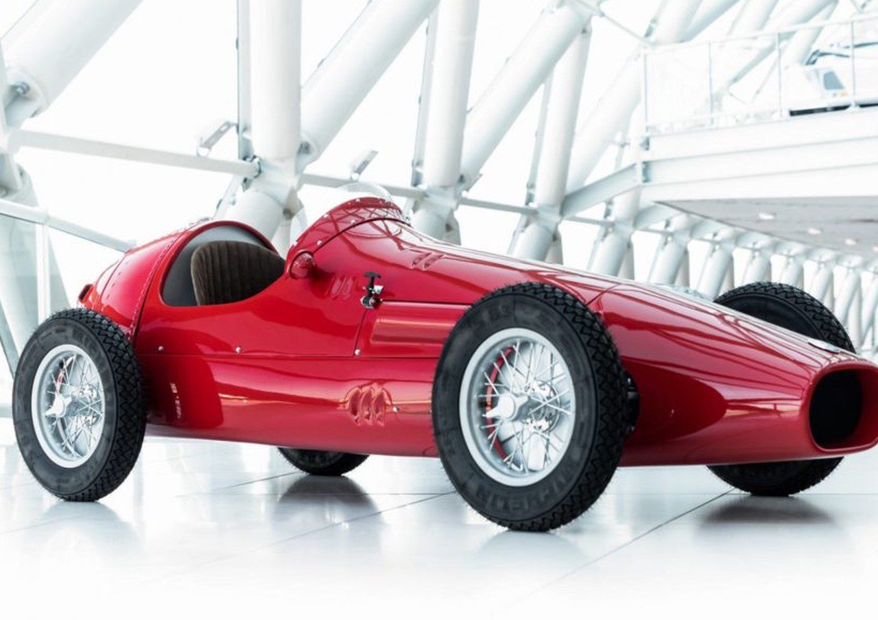 Een rode 250F-raceauto staat geparkeerd in een gebouw.