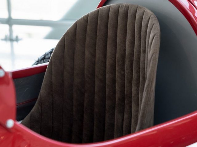Een close-up van de stoel van een rode 250F-racewagen.