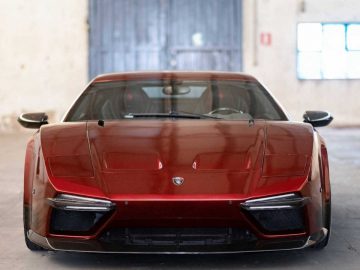 Een rode sportwagen van Ares Design staat geparkeerd in een garage.