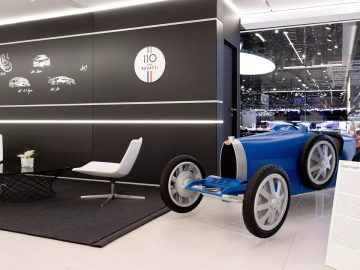 In een showroom staat een blauwe Bugatti tentoongesteld.
