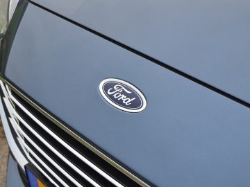 Een close-up van het Ford Focus-logo op de motorkap van een blauwe auto.