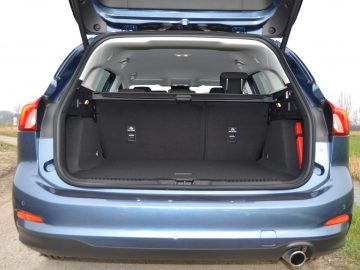De focus van het beeld ligt op de kofferbak van een blauwe SUV met de kofferbak open.