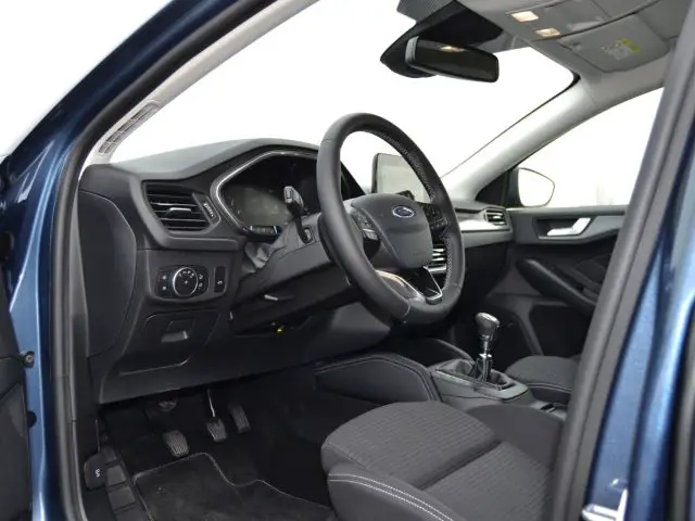 Het interieur van een blauwe auto met een stuur en dashboard in focus.