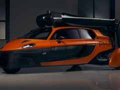 Een futuristische oranje Pal-V staat geparkeerd in een garage.