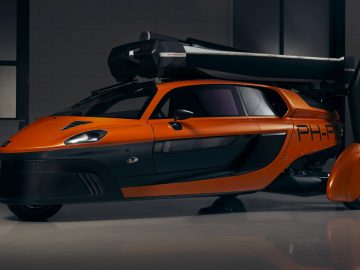 Een futuristische oranje Pal-V staat geparkeerd in een garage.