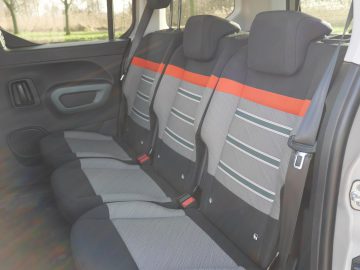 De achterbank van een Berlingo met grijze en oranje stoelen.