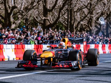 Een Red Bull-racewagen rijdt voor een menigte door een straat in Tokio.