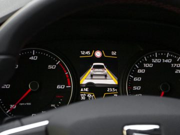 Het dashboard van een auto met een snelheidsmeter en veiligheidsvoorzieningen.