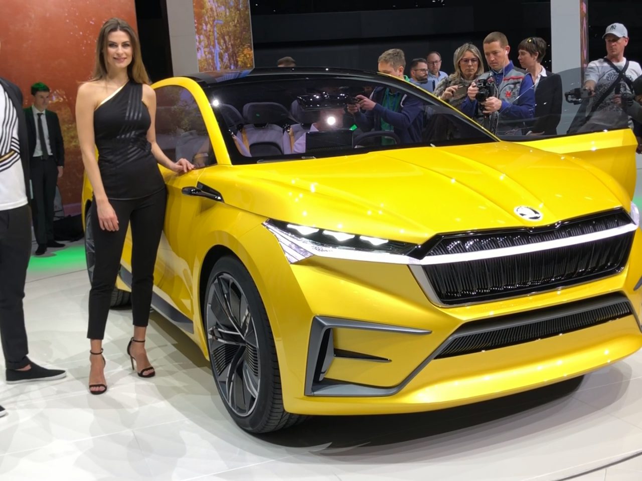 Twee mensen staan naast een gele Toyota SUV op een autoshow.