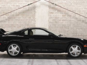 Een zwarte Supra-sportwagen staat geparkeerd in een garage.