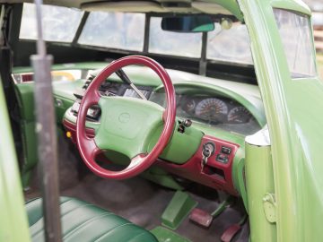 Het interieur van een groene Thunderbird-auto met een stuur en dashboard.