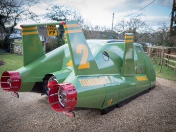 Een groene Thunderbird staat geparkeerd op een oprit.