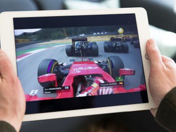Een persoon die een tablet vasthoudt met een Formule 1-raceauto erop.