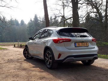 De achterkant van een zilveren Ford Focus Active geparkeerd op een onverharde weg.