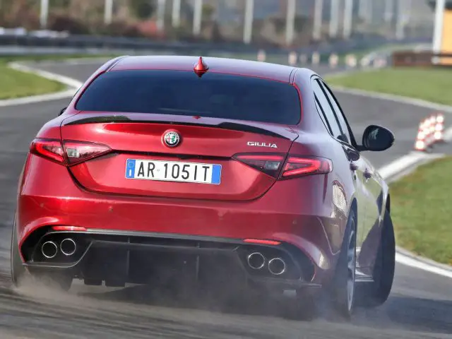 Een rode Alfa Romeo die op een circuit rijdt, een model van de FCA-groep.