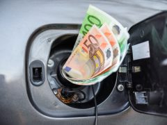 Een benzine-eurobiljet wordt in de benzinetank van een auto gepompt.