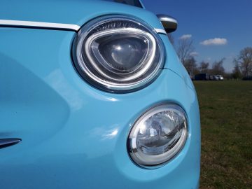 Een close-up van de koplampen van een blauwe 500C Spiaggina '58-auto.