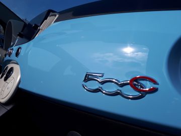 Een close-up van een blauwe 500C Spiaggina '58-auto met een logo erop.