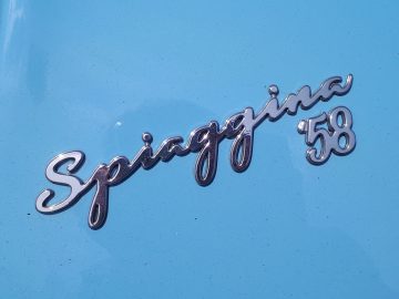 Een close-up van een blauwe auto met het woord "500C Spiaggina '58" erop.