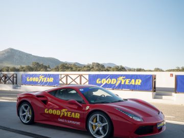 Een rode Ferrari-sportwagen met Goodyear Eagle F1-banden staat geparkeerd op een parkeerplaats.