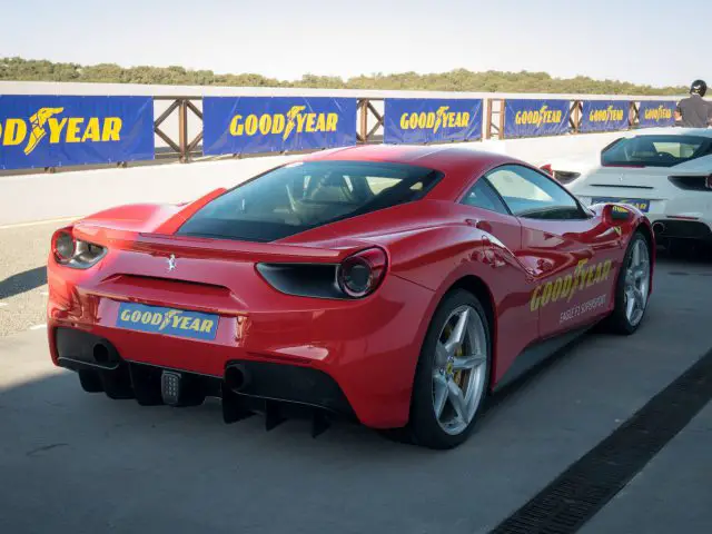 Naast een andere auto staat een rode Ferrari-sportwagen met Goodyear Eagle F1-banden geparkeerd.