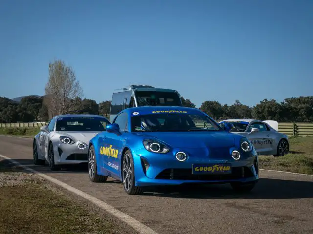 Twee blauwe sportwagens met Goodyear Eagle F1-banden rijden over een landweg.
