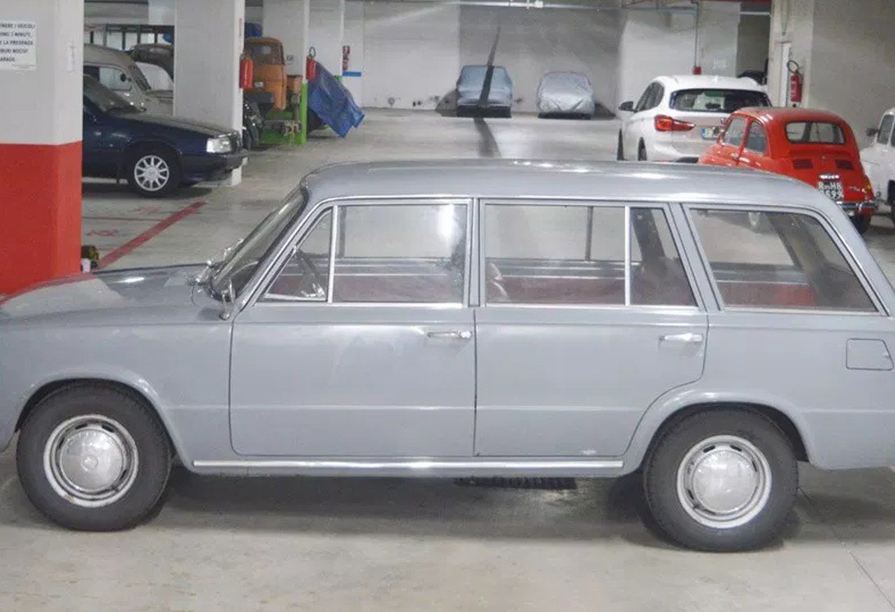 Een oude grijze auto staat geparkeerd in een garage 124.