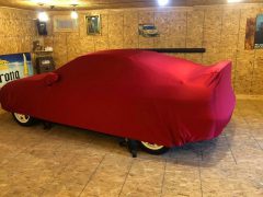 Een rode Integra overdekt in een garage.