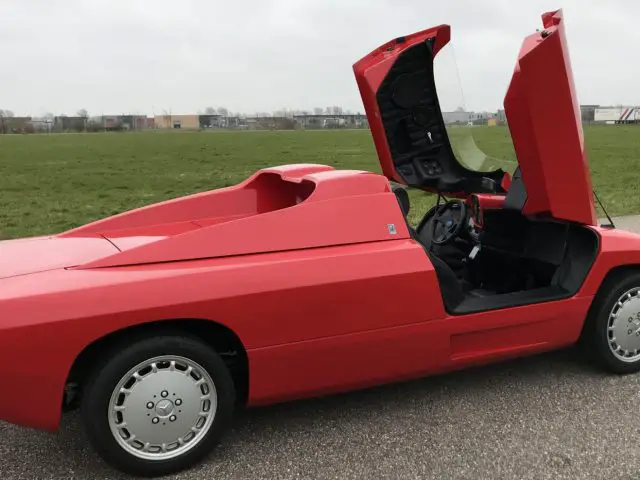 Een rode Isdera-sportwagen met open deuren.