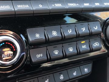 Het dashboard van een Kia Sportage, met verschillende knoppen en bedieningselementen.