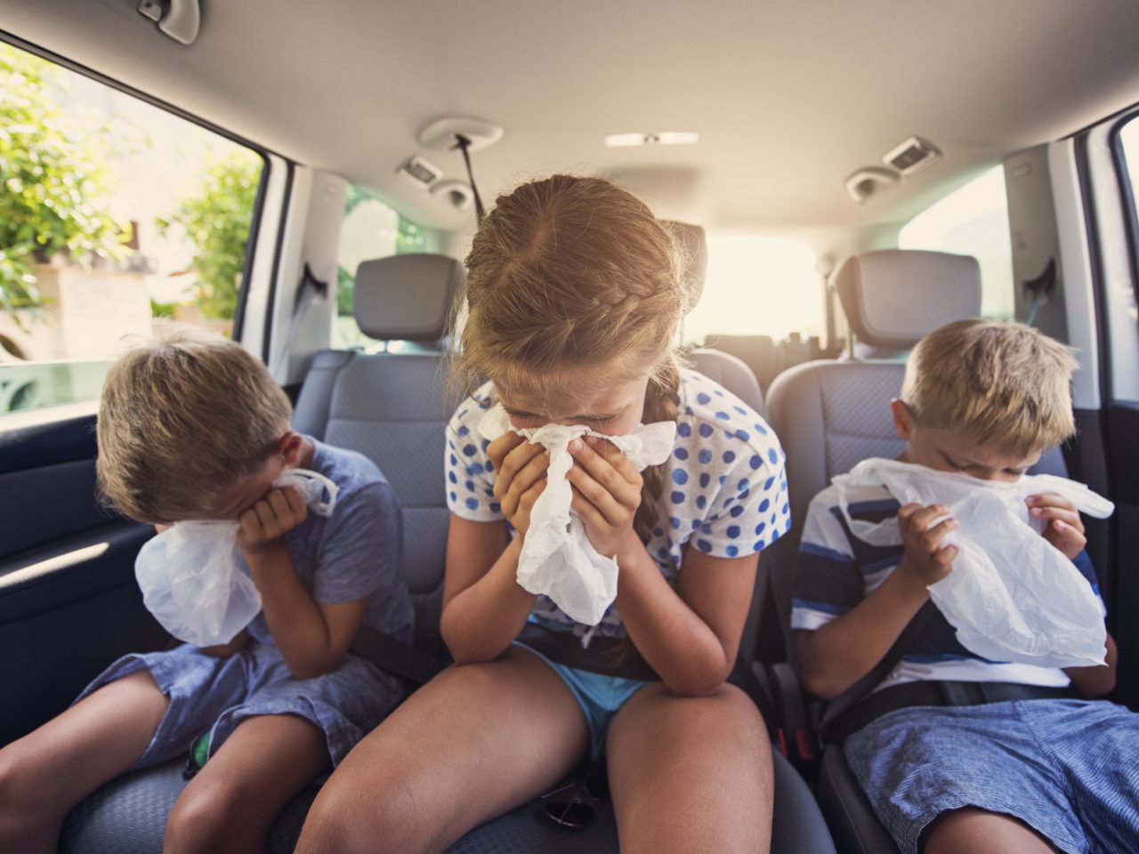 Drie kinderen zitten met waarschijnlijk in de achterbank van een auto.