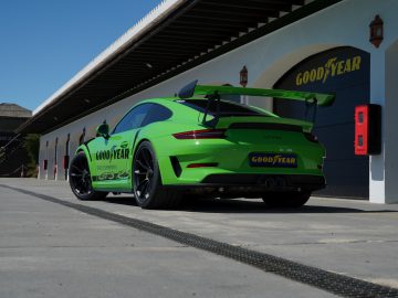 Een groene Porsche 911 GT3 RS uitgerust met Goodyear Eagle F1-banden geparkeerd voor een garage.