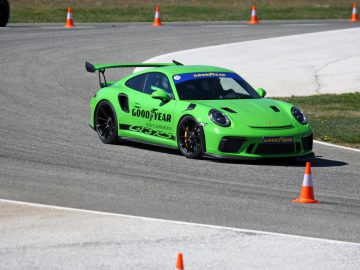 Een groene Porsche GT3 racet rond kegels op een circuit met Goodyear Eagle F1-banden.
