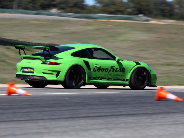 Een groene Porsche GT3 uitgerust met Goodyear Eagle F1-banden die rond kegels op een circuit racet.