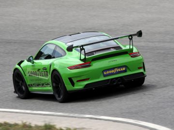 Een groene Porsche 911 GT3 met Goodyear Eagle F1-banden racet op een circuit.
