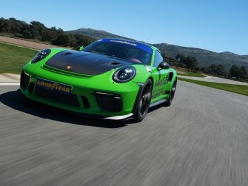 Een groene Porsche GT3 met Goodyear Eagle F1-banden rijdend op een circuit.