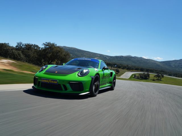 Een groene Porsche 911 GTS met Goodyear Eagle F1-banden rijdend op een bergweg.
