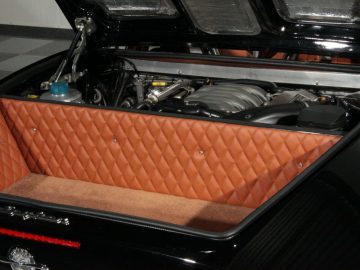De kofferbak van een zwarte Spyker-sportwagen met een bruin interieur.