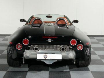 Een zwarte Spyker-sportwagen op een geblokte vloer.