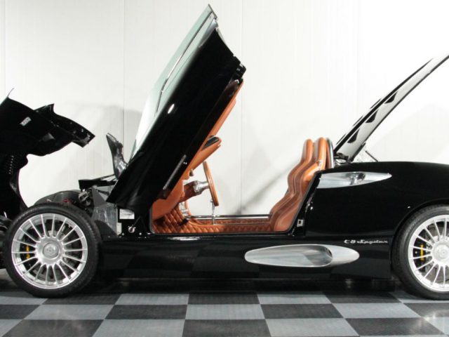Een zwarte Spyker-sportwagen met open deuren.