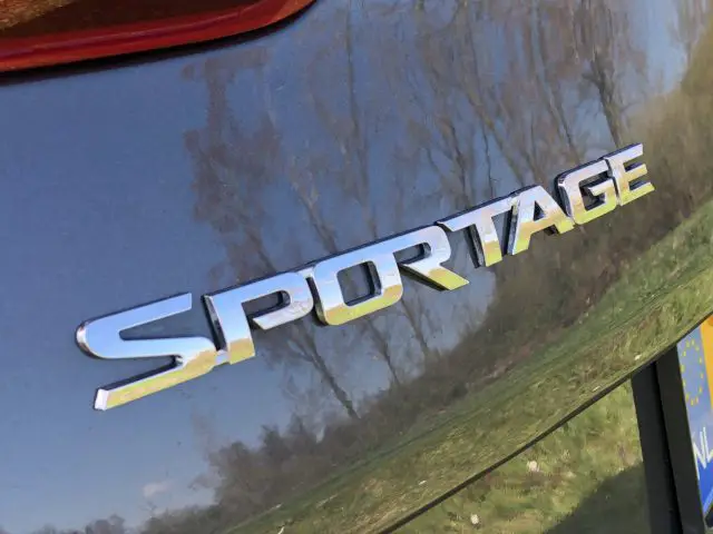 Een close-up van een zilveren Kia Sportage met het woord 'sportage' erop.