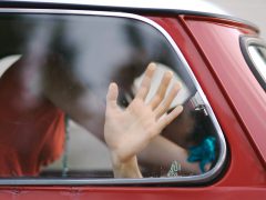 Een vrouw fileflirt door met haar hand uit het raam van een auto te zwaaien.