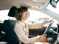 Een vrouw die lachend autorijdt, heeft een goede autoverzekering.