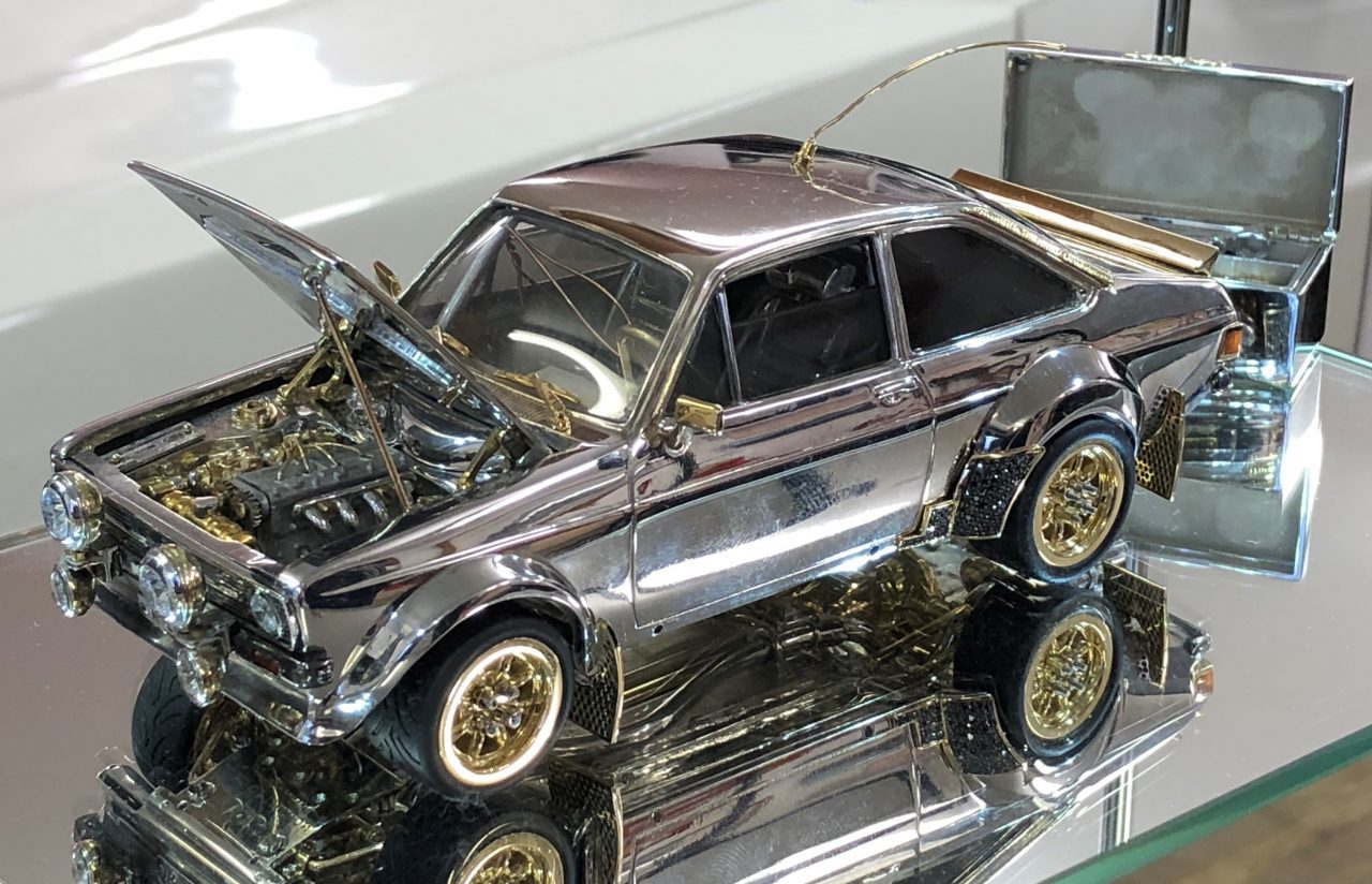 Een zilveren Ford speelgoedauto staat tentoongesteld in een glazen vitrine en rijdt niet.